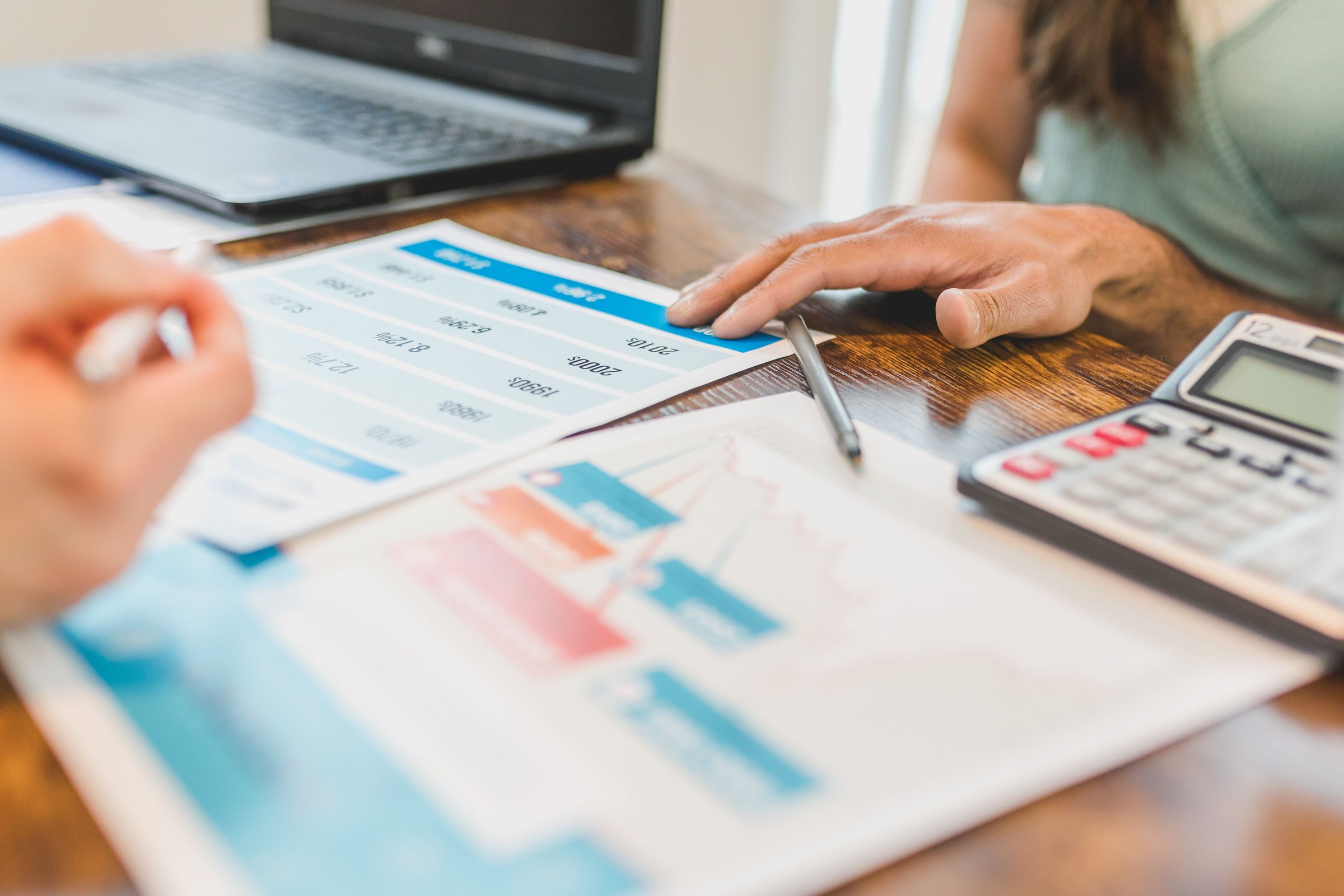 Two people reviewing financial charts and a returns table with a calculator at a desk