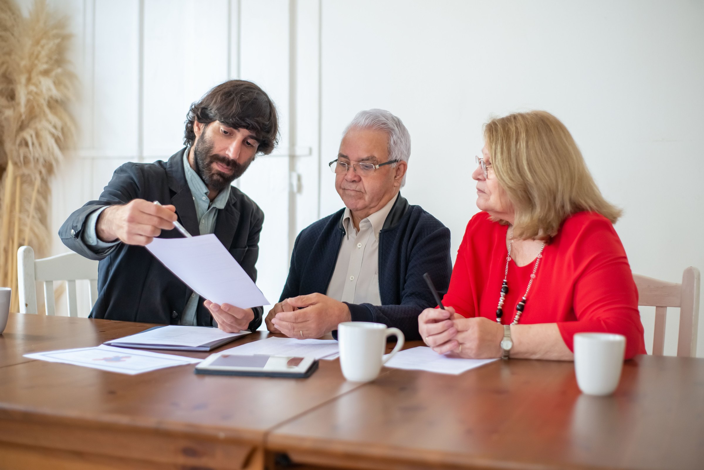 An advisor walking an older couple through a document at their dining table